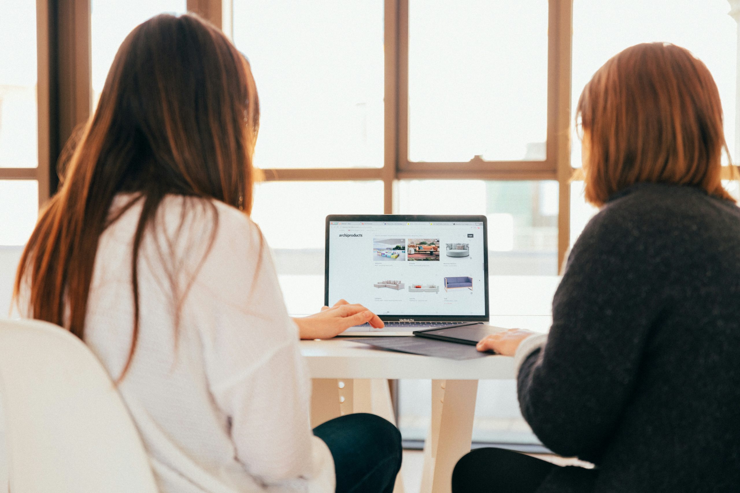 Two women sitting in front of a laptop working